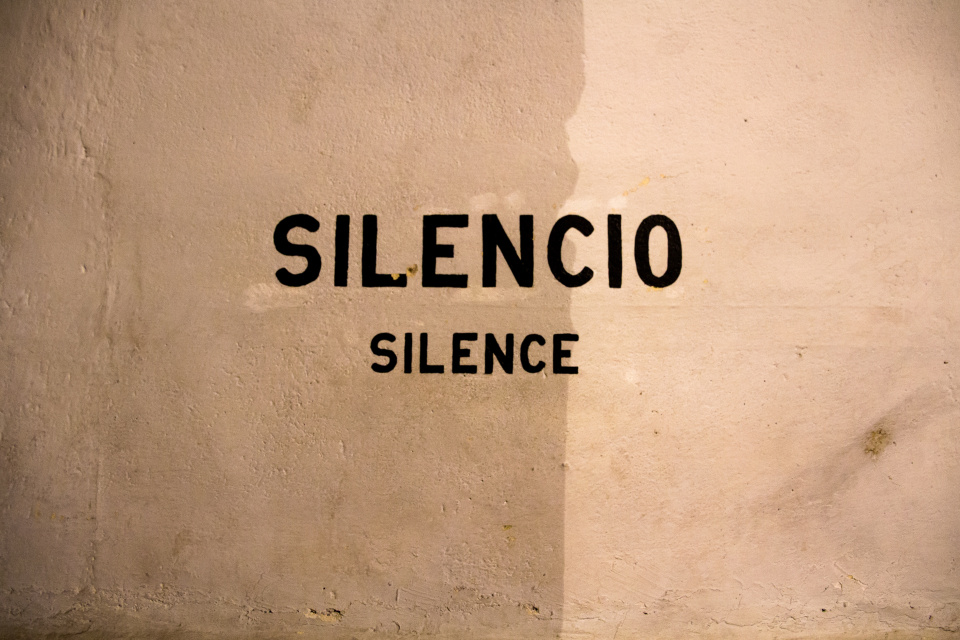 Photo of a wall that says "Silencio" (in Spanish) with "Silence" underneath it