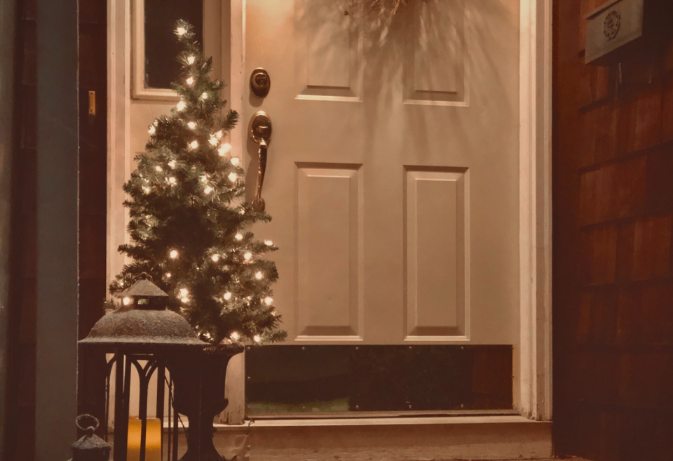 Home with a small Christmas tree lit in front of the front door