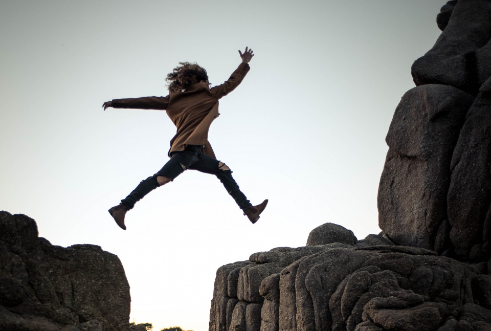 person jumping from one rock to the next