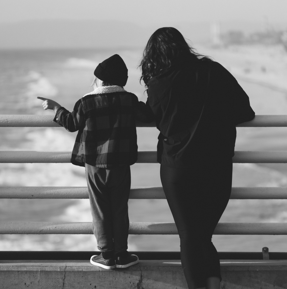 a mother and child looking out at crashing waves