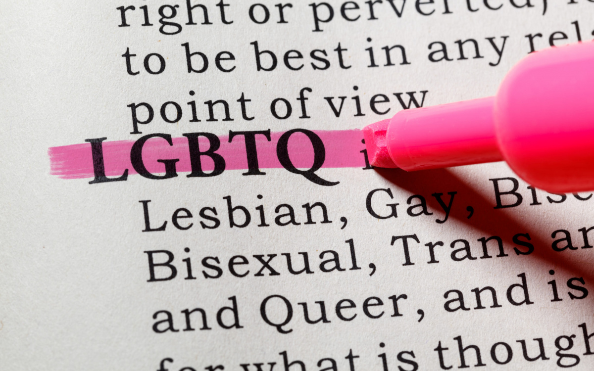 A close-up photograph of a dictionary page with the word 'LGBTQ' highlighted in pink.